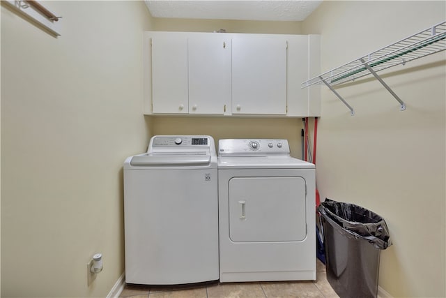 washroom with cabinets, light tile patterned floors, a textured ceiling, and washing machine and clothes dryer