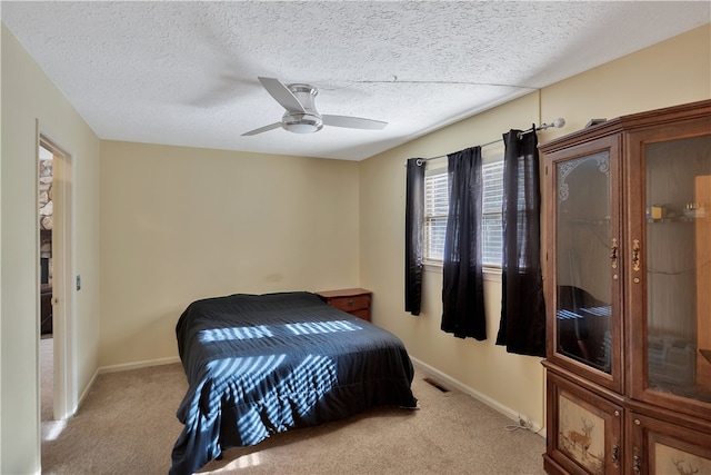 bedroom with light carpet, a textured ceiling, and ceiling fan