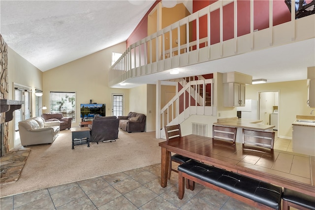 dining space with carpet flooring, a textured ceiling, sink, high vaulted ceiling, and washer / dryer