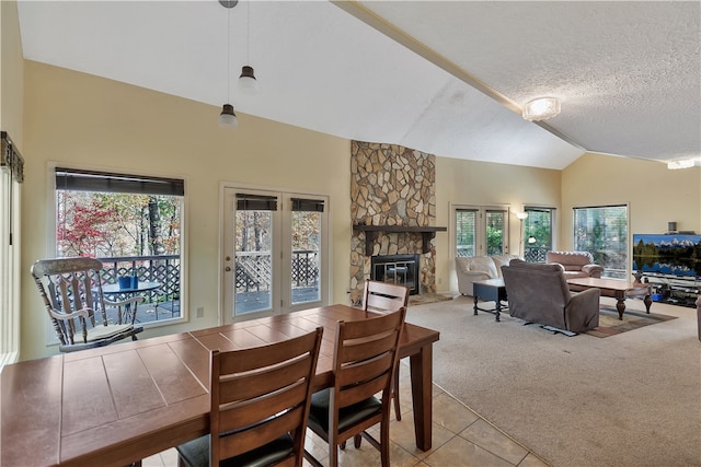 carpeted dining area featuring a fireplace, a textured ceiling, vaulted ceiling, and a wealth of natural light