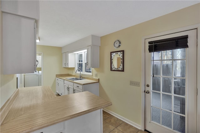 kitchen with white cabinets, plenty of natural light, separate washer and dryer, and sink