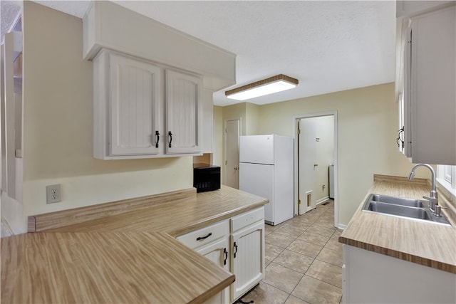 kitchen with sink, white cabinets, a textured ceiling, and white refrigerator