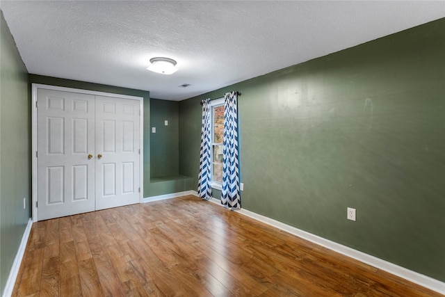 unfurnished bedroom with hardwood / wood-style flooring, a textured ceiling, and a closet