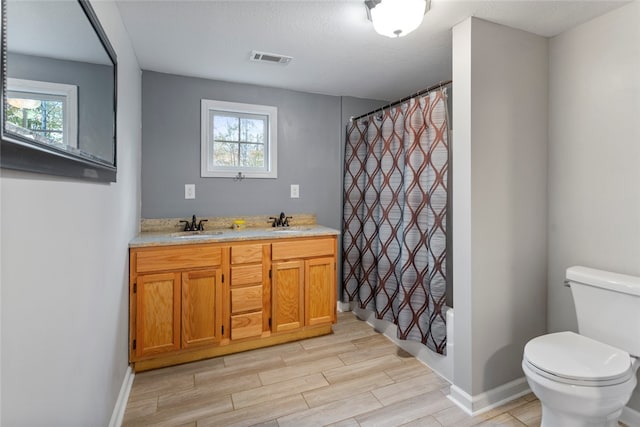 bathroom with hardwood / wood-style floors, vanity, a healthy amount of sunlight, and toilet