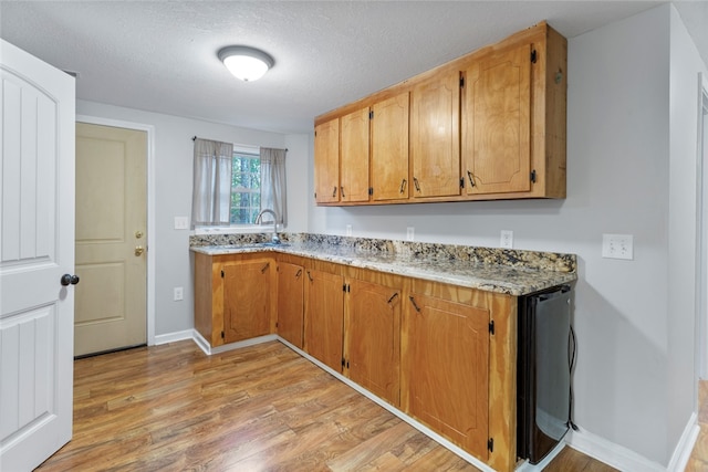 kitchen featuring a textured ceiling, light hardwood / wood-style floors, and sink