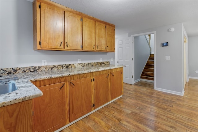 kitchen with light stone countertops, a textured ceiling, and light hardwood / wood-style flooring