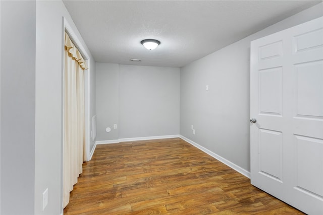 empty room with wood-type flooring and a textured ceiling