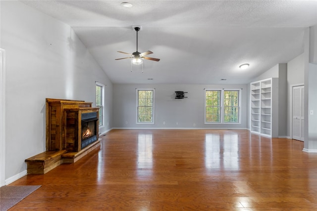 unfurnished living room with ceiling fan, high vaulted ceiling, wood-type flooring, and a textured ceiling