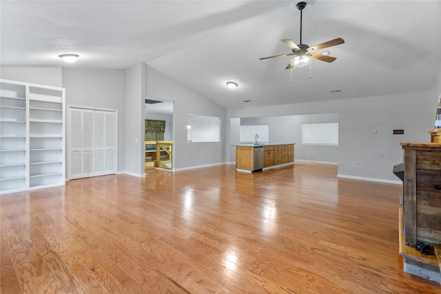 unfurnished living room featuring vaulted ceiling, ceiling fan, light wood-type flooring, a textured ceiling, and a fireplace