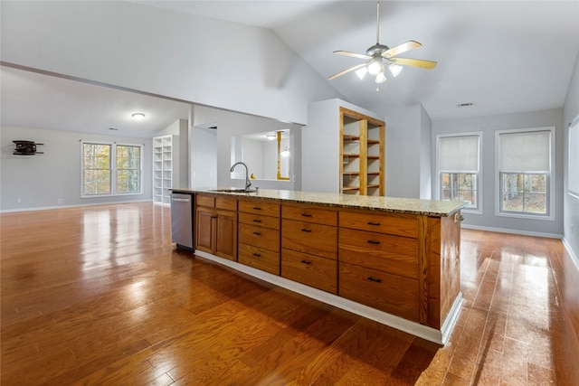 kitchen with ceiling fan, sink, wood-type flooring, dishwasher, and an island with sink