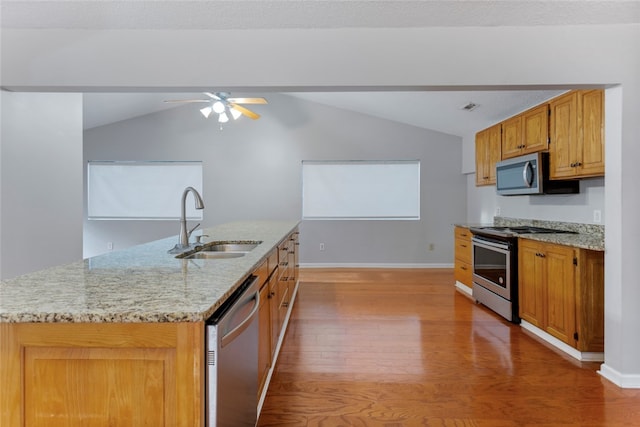 kitchen with stainless steel appliances, sink, a center island with sink, hardwood / wood-style floors, and lofted ceiling