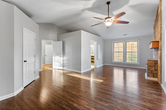 unfurnished living room with ceiling fan, a stone fireplace, dark hardwood / wood-style flooring, and vaulted ceiling