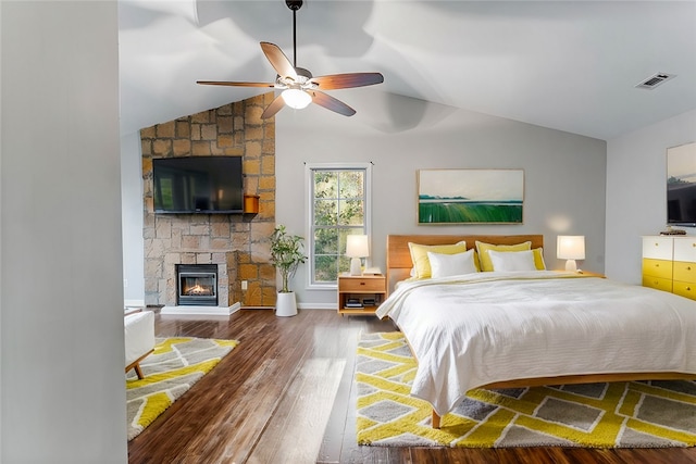 bedroom featuring ceiling fan, a fireplace, vaulted ceiling, and hardwood / wood-style flooring