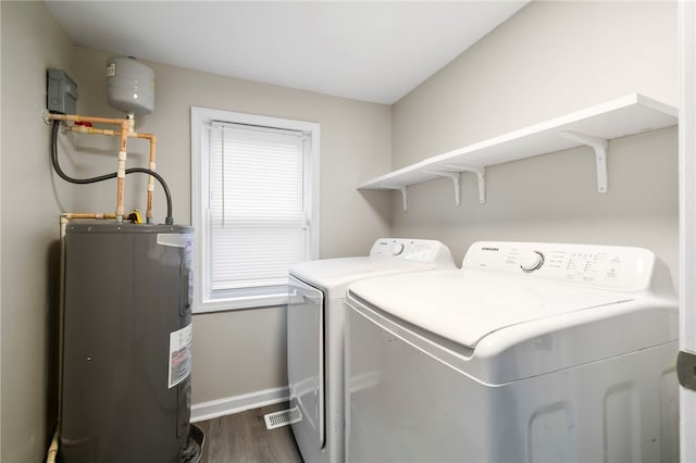 laundry area featuring dark hardwood / wood-style floors, washing machine and dryer, and electric water heater