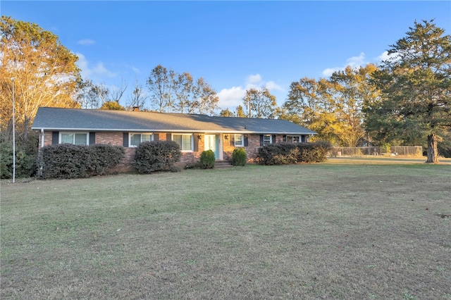 single story home featuring brick siding, a chimney, a front yard, and fence