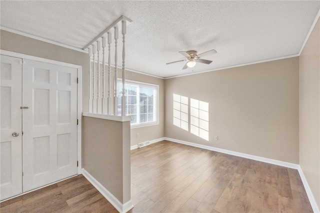 entrance foyer with wood finished floors, ornamental molding, and a ceiling fan