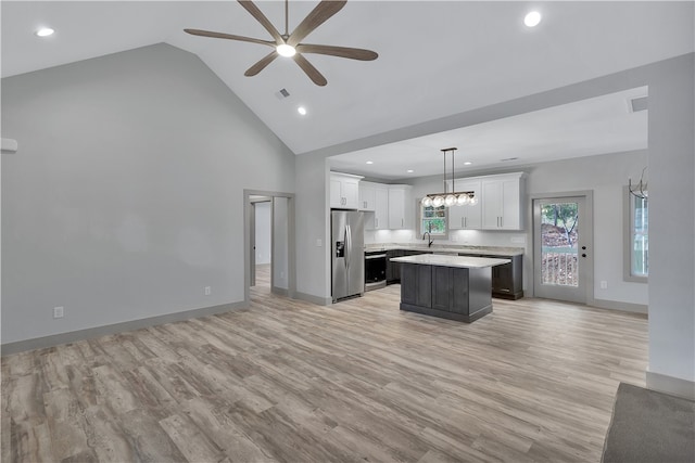 kitchen with white cabinets, a kitchen island, pendant lighting, and light wood-type flooring