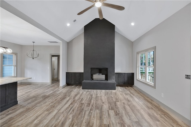 unfurnished living room featuring a fireplace, high vaulted ceiling, light hardwood / wood-style floors, and ceiling fan with notable chandelier