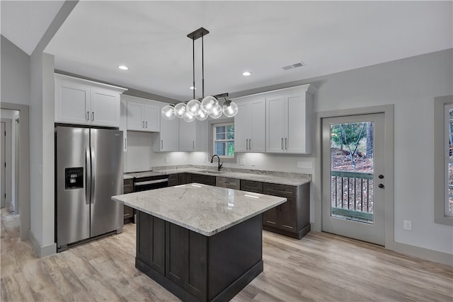 kitchen featuring stainless steel fridge with ice dispenser, white cabinetry, a kitchen island, and hanging light fixtures