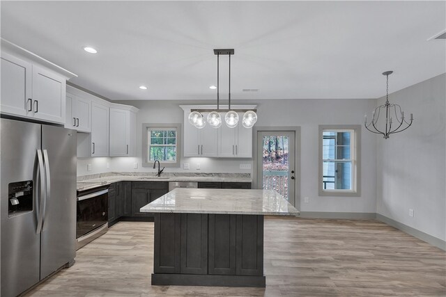 kitchen with white cabinets, decorative light fixtures, stainless steel appliances, and a kitchen island