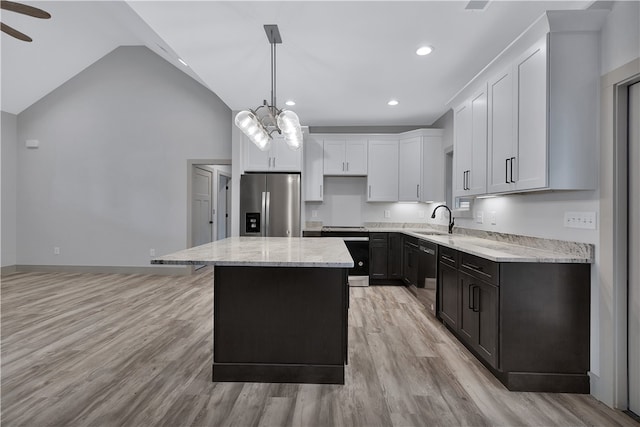 kitchen featuring stainless steel appliances, a kitchen island, white cabinetry, and lofted ceiling