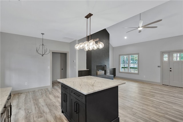 kitchen with a center island, decorative light fixtures, a wood stove, and light hardwood / wood-style floors