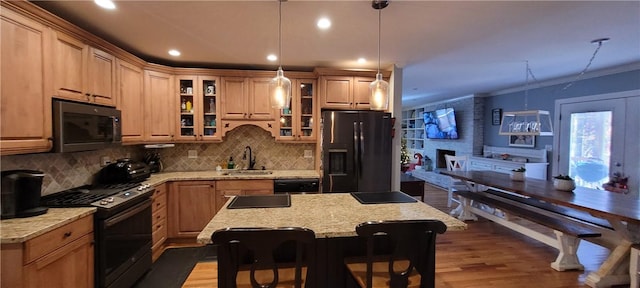 kitchen with dark wood-type flooring, black appliances, a kitchen breakfast bar, sink, and a kitchen island