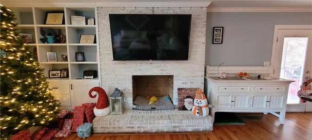 living room with hardwood / wood-style flooring, crown molding, and a brick fireplace