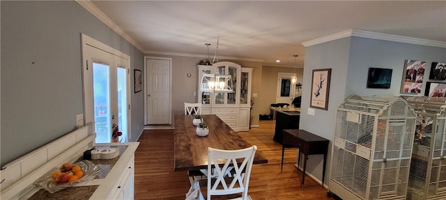 dining area with a chandelier, wood-type flooring, and crown molding