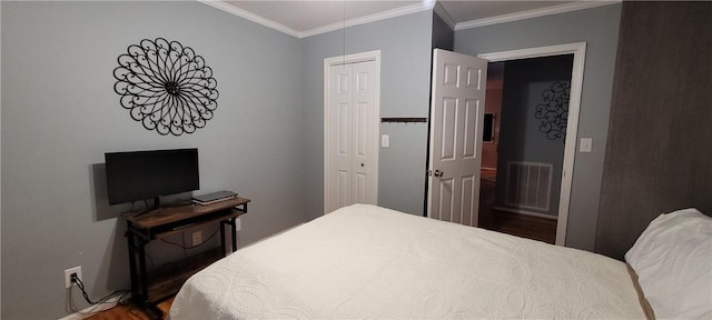 bedroom with wood finished floors, visible vents, a closet, and crown molding