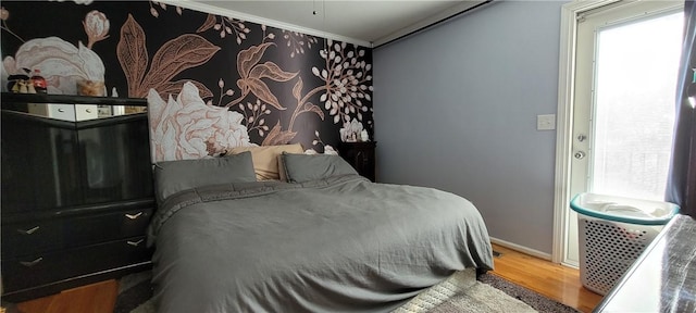 bedroom with baseboards, wood finished floors, and ornamental molding