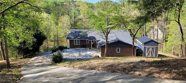 view of front of home with brick siding and a view of trees