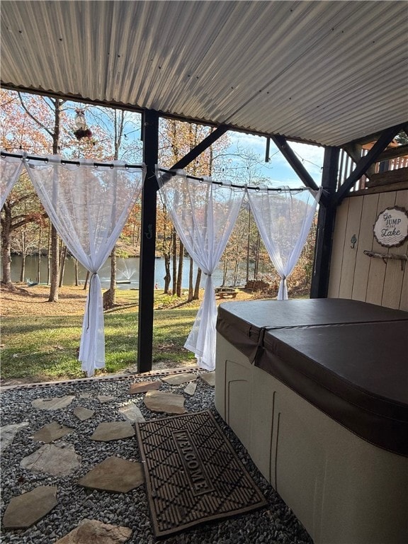 view of patio featuring a water view and a hot tub