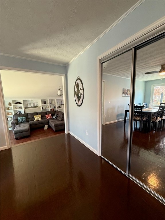 corridor with hardwood / wood-style flooring, built in shelves, ornamental molding, and a textured ceiling