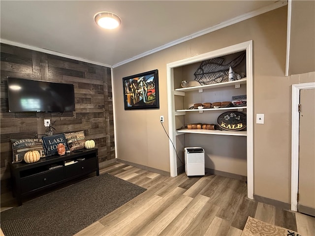 living room with crown molding, light hardwood / wood-style flooring, and wooden walls