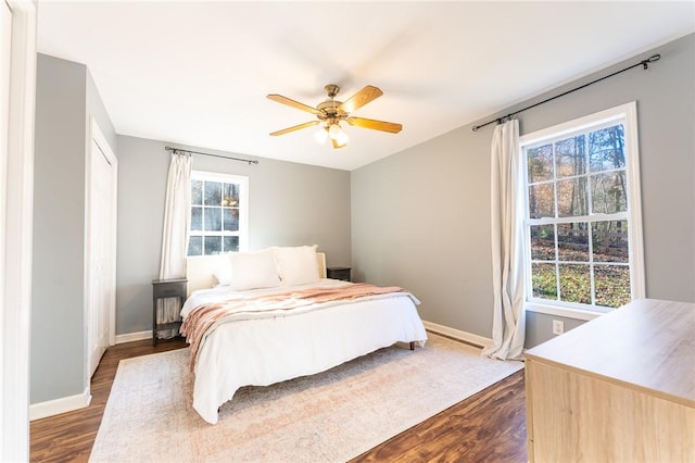 bedroom with ceiling fan, baseboards, and dark wood-style flooring