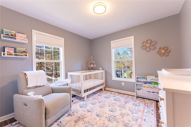 bedroom featuring hardwood / wood-style flooring, multiple windows, and a nursery area