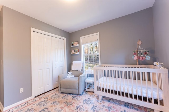 bedroom featuring a nursery area, a closet, and baseboards