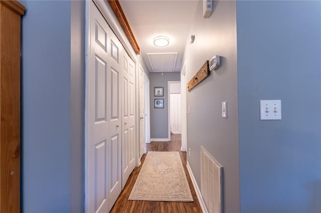 hallway featuring dark wood-style floors, attic access, visible vents, and baseboards