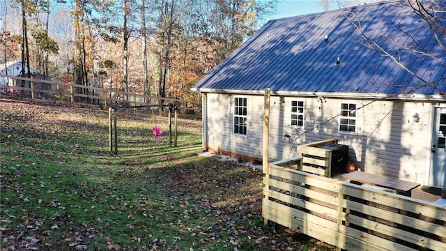 rear view of house featuring metal roof, a lawn, and fence