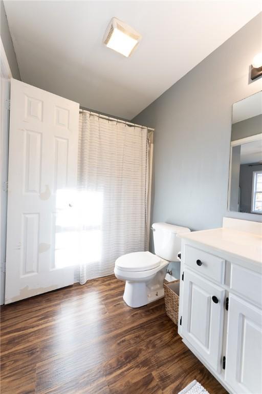 full bath featuring vanity, a shower with shower curtain, wood finished floors, and toilet