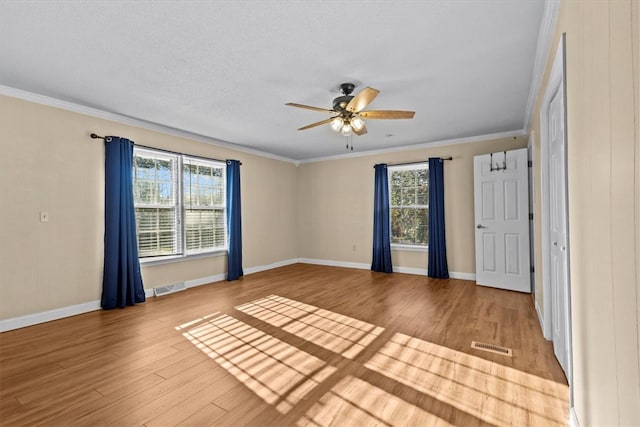 unfurnished room featuring hardwood / wood-style floors, a healthy amount of sunlight, crown molding, and a textured ceiling