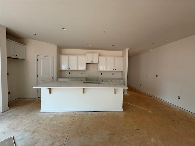 kitchen with a spacious island, white cabinetry, concrete floors, and a kitchen breakfast bar