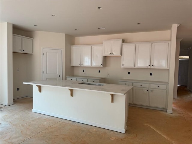 kitchen featuring a center island, white cabinetry, unfinished concrete flooring, and a kitchen bar