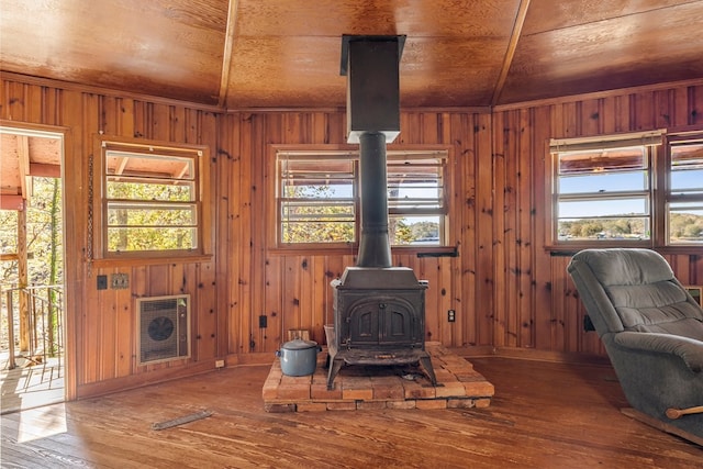 living room with a wood stove, wood walls, and hardwood / wood-style flooring