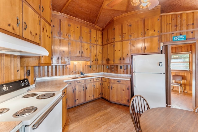 kitchen with light wood-type flooring, lofted ceiling, white appliances, and wooden walls