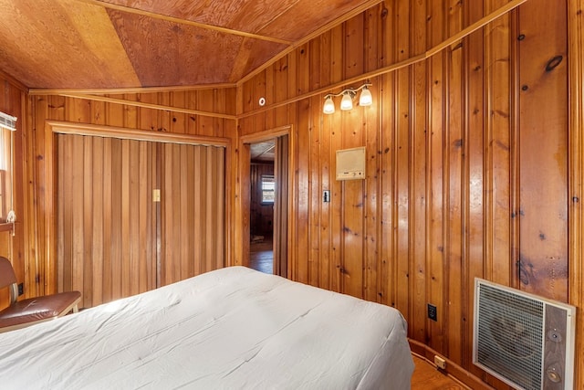 bedroom with heating unit, vaulted ceiling, wood-type flooring, wooden ceiling, and wood walls