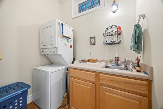 washroom with sink, cabinets, and stacked washer / drying machine