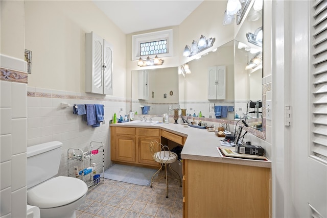 bathroom featuring tile patterned flooring, vanity, toilet, and tile walls