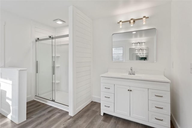 bathroom with vanity, wood-type flooring, and a shower with door